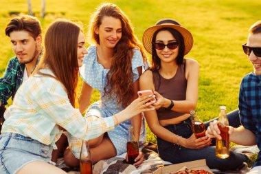 Gençler doğada piknik yaparlar. Genç arkadaşlar rahatlar, pizza yer ve içki içerler. Bir grup genç gün batımında bir yaz parkında çimlerin üzerinde otururken iletişim kuruyor. Arkadaşlar boş zamanlarında rahatlar..