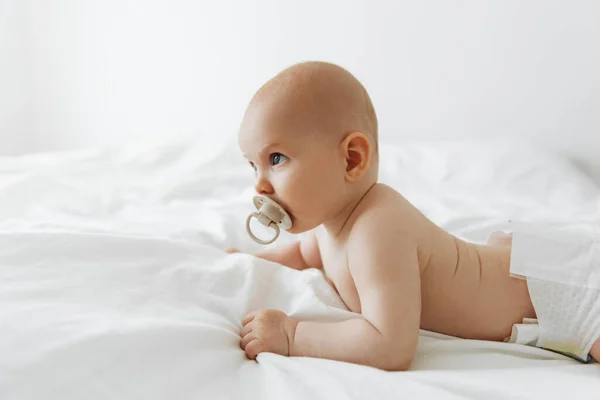 Newborn Baby Sucks Pacifier Lies White Bed Home White Sunny — Zdjęcie stockowe