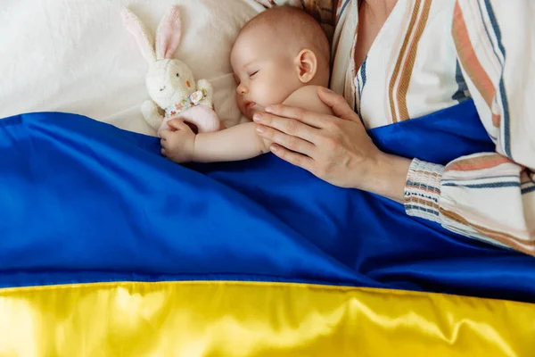 ภาพถ ายใกล ดของแม บทารกแรกเก ดของเธอนอนบนเต ยงท านปกคล วยธงส าและส เหล ภาพสต็อก