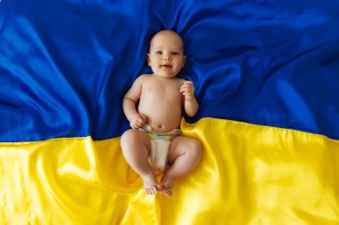 Pray for Ukraine A smiling little girl lies on the Ukrainian Blue and Yellow flag. The child gives hope for the best. protest against war, peace, end of aggression