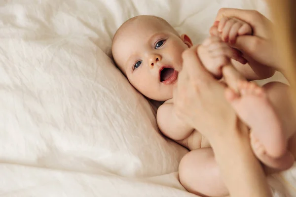 Portrait of joy, love, loving family Caring and loving mother playing with a cute little smiling baby. Mom touches a cute baby in a diaper while having a good time in a white bedroom