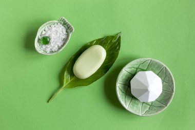 Güzel SPA konseptinin aromatik banyo tuzu, sabun ve taze yeşil bitki yapraklarıyla yakın plan fotoğrafı.