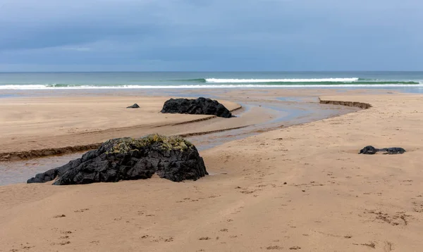 아일랜드 런던데리 카운티의 데메스네 해변에서 밀물과 바위가 해변을 사람들 왕좌의 로열티 프리 스톡 이미지