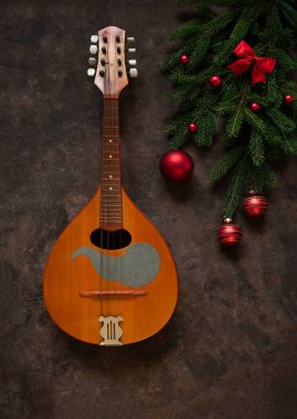 Old mandolin and fir-tree branches with Christmas decor. Christmas and New Year's concept. Top view, close-up on dark concrete background..	