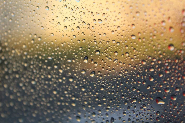 雨后玻璃上的水滴的漂亮背景 雨后大水滴的照片 杯子上的水 美丽多彩的背景 玻璃杯后面有不同的颜色 — 图库照片