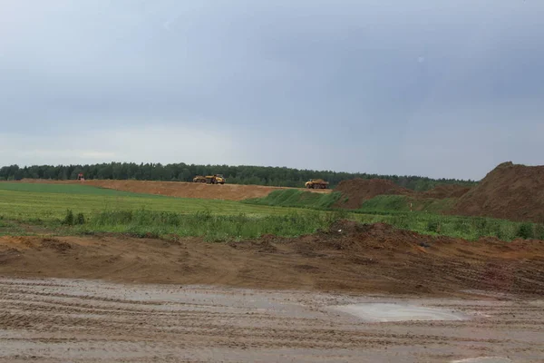 Arabalar yeni bir yol / fotoğraf yol inşaatı için kum taşır. Yol yüzeyi kumdan yapılmıştır. Arabalar yeni bir pist oluşturmak için malzeme taşır.