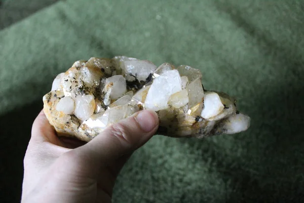 close-up of natural unprocessed rock crystal in a woman\'s hand / photo of a beautiful unprocessed stone. a woman holds a crystal in her hand. large natural rhinestone. white, transparent color. inclusions of yellow and black.