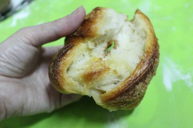 Ekmek tutan bir elin kırık bir topuz / fotoğrafını tutan bir elin yakın çekimi. Taze turta bozulmuş. Kekin içindeki pişmiş hamur neye benziyor?.