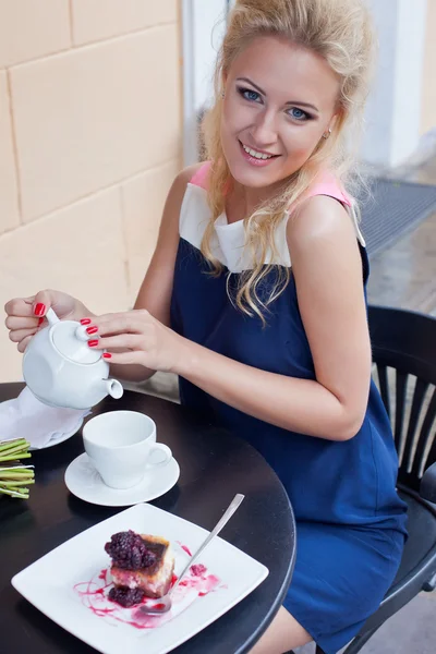 Een mooie jonge blonde meisje in de zomer jurk aan de tafel in pav — Stockfoto