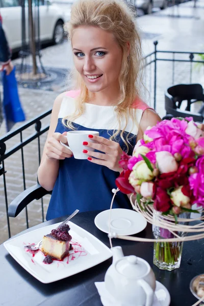 Krásná mladá blondýnka v létě šaty u stolu v pav — Stock fotografie