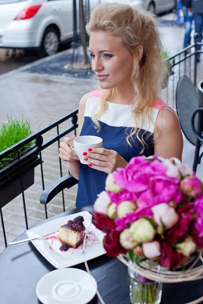 Une belle jeune fille blonde en robe d'été à la table en pav — Photo