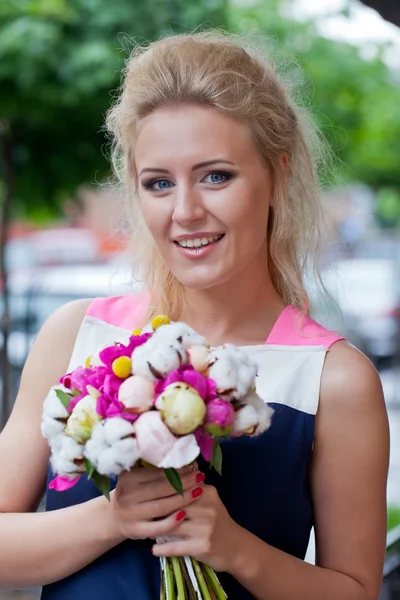 Una hermosa joven en vestido de verano con un ramo de flores i — Foto de Stock