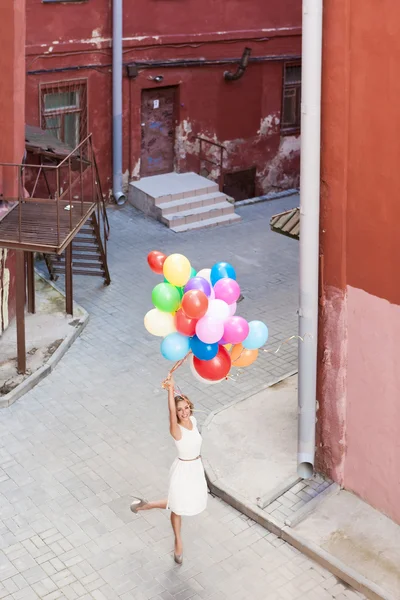 Beautiful lady in retro outfit holding a bunch of balloons — Stock Photo, Image