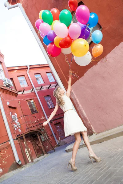 Beautiful lady in retro outfit holding a bunch of balloons — Stock Photo, Image