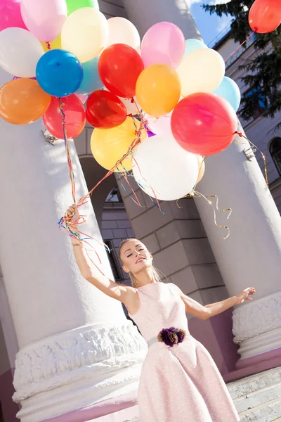 Beautiful lady in retro outfit holding a bunch of balloons — Stock Photo, Image