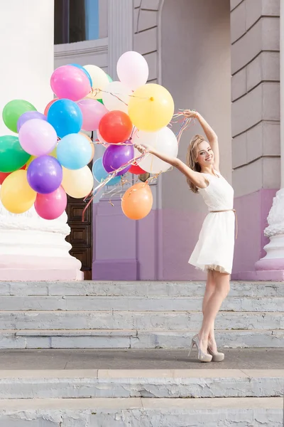 Beautiful lady in retro outfit holding a bunch of balloons — Stock Photo, Image