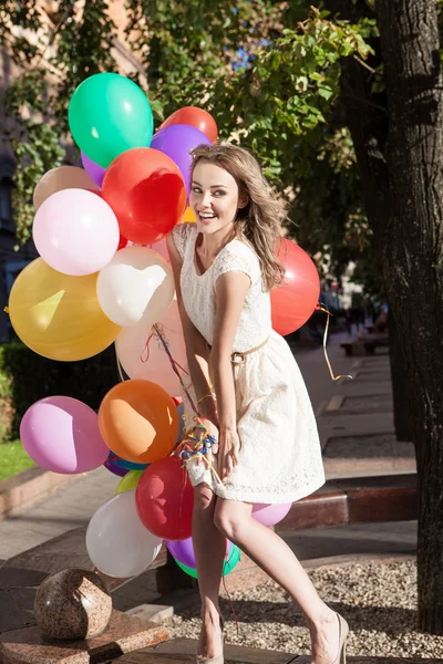 Beautiful lady in retro outfit holding a bunch of balloons — Stock Photo, Image