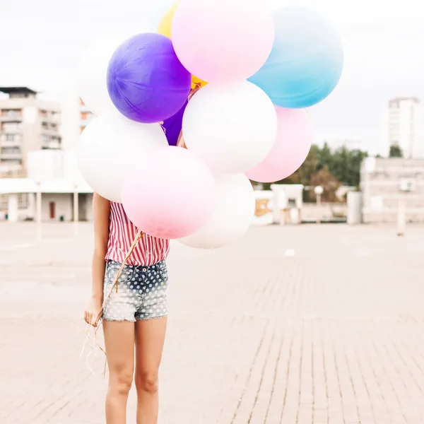 Young beautiful lady holding bunch of bright balloons — Stock Photo, Image