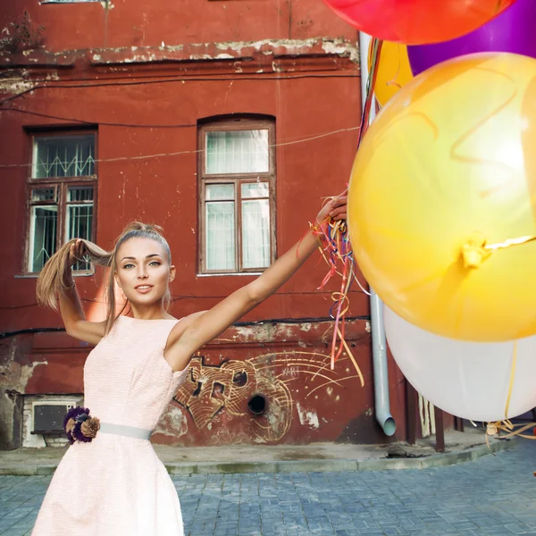 Beautiful lady in retro outfit holding a bunch of balloons betwe — Stock Photo, Image