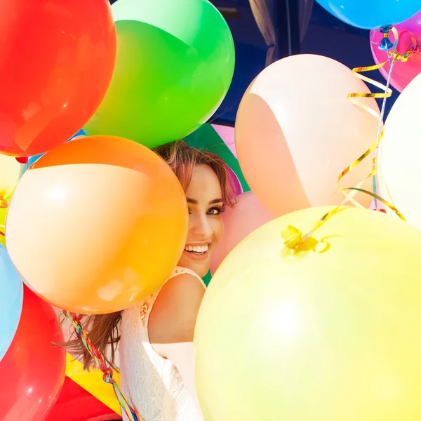 Beautiful lady in retro outfit holding a bunch of balloons on th — Stock Photo, Image
