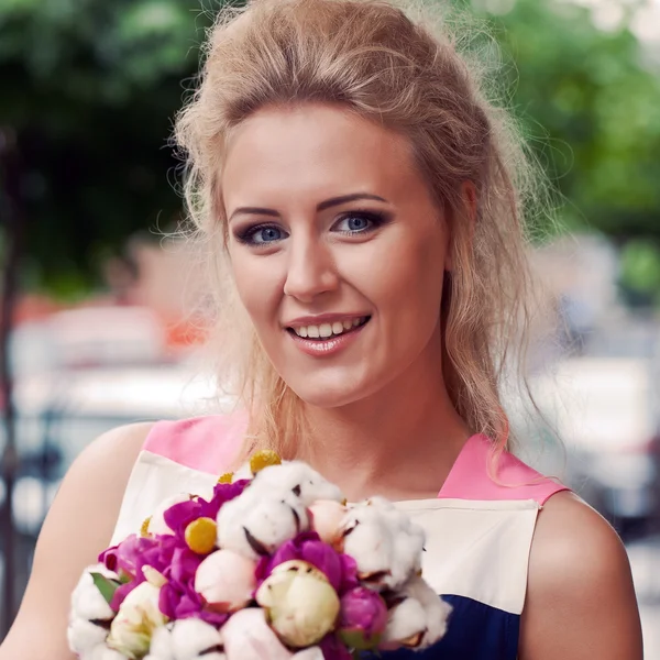 Uma bela jovem no vestido de verão com um monte de flores i — Fotografia de Stock