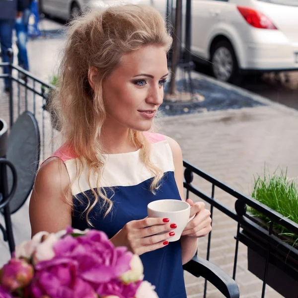 Una bella giovane ragazza bionda in abito estivo a tavola in pav — Foto Stock