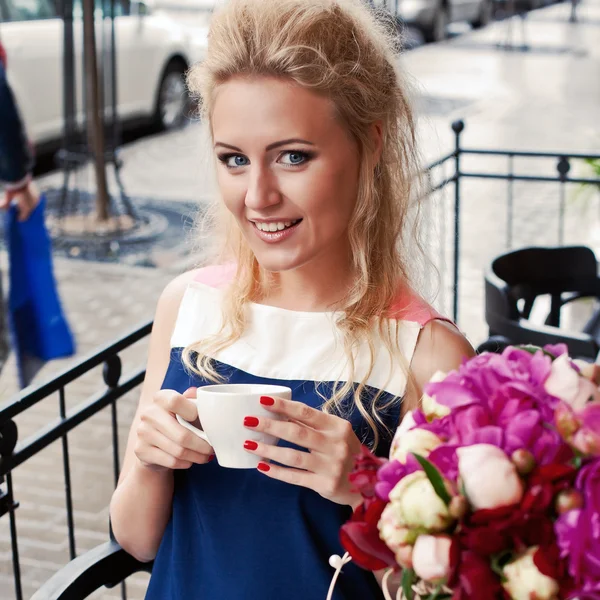 Een mooie jonge blonde meisje in de zomer jurk aan de tafel in pav — Stockfoto