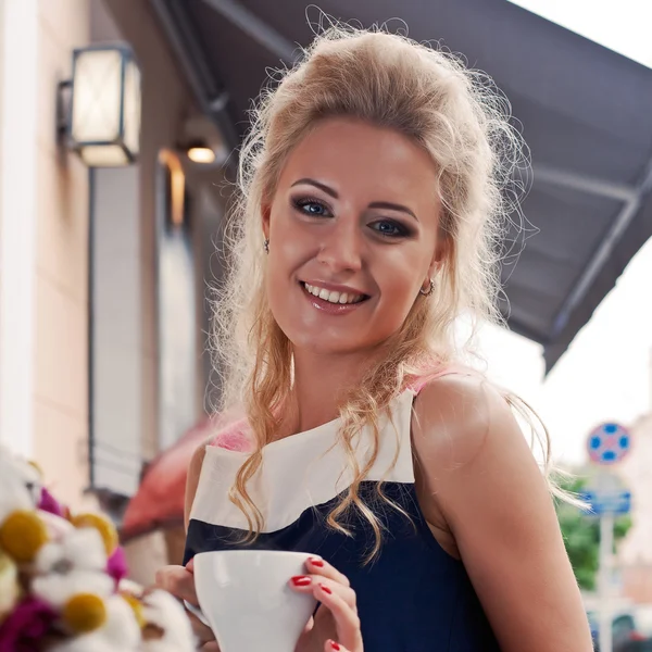 Een mooie jonge blonde meisje in de zomer jurk aan de tafel in pav — Stockfoto
