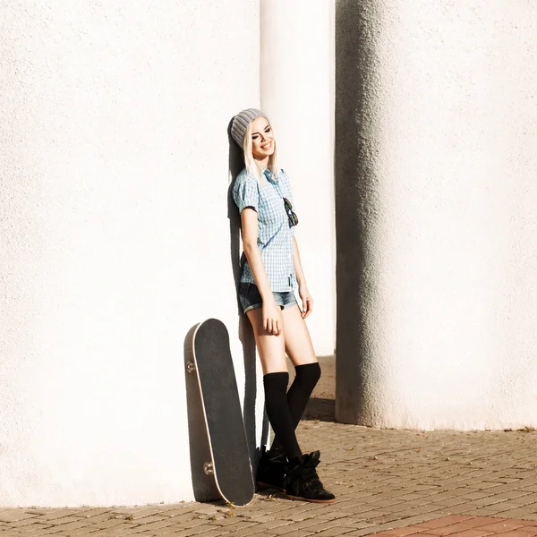 Prachtige blond meisje in korte broek met skateboard — Stockfoto