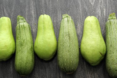 Taze, çiğ ve lezzetli taze hasat edilmiş çakallar ve yeşil kabak soymaya, doğramaya ve ahşap bir masada pişirmeye hazır.
