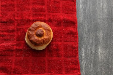 Taze, lezzetli ve taze yapılmış tahtadan bir masada, kahvaltıda sıcak kahvenin eşlik ettiği renkli bir peçeteyle yenmeye hazır tatlı bir ekmek.