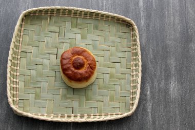 Taze, lezzetli ve taze yapılmış tahtadan bir masada, kahvaltıda sıcak kahvenin eşlik ettiği renkli bir peçeteyle yenmeye hazır tatlı bir ekmek.