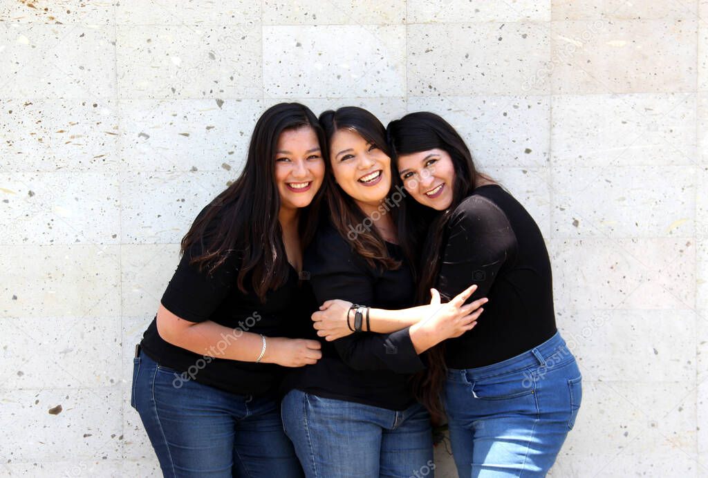 Happy black straight hair latin adult sisters dressed in black for family photo shoot in harmony and joy