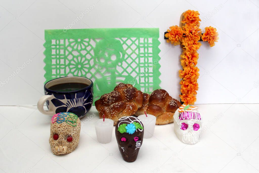 Sweet in the shape of a skull made of sugar, chocolate and amaranth as an offering for the Day of the faithful departed and all the saints together with cempasuhil, candles and photo frame