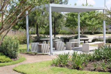 Güvenli ve güzel bir yerde aile ve mahalle için bankları, masaları ve oyunları olan açık hava topluluk alanı.