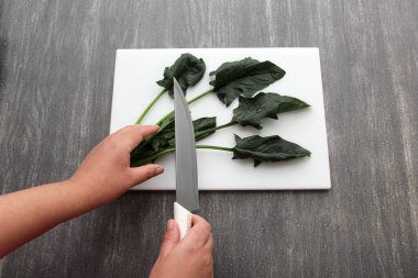 Tahta masada taze yeşil ıspanak ve sağlıklı bir salata ya da vitamin dolu bir spa için bıçakla tahta doğrama.