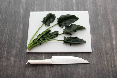 Tahta masada taze yeşil ıspanak ve sağlıklı bir salata ya da vitamin dolu bir spa için bıçakla tahta doğrama.