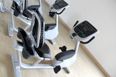 Kardiyo, tonlama bacakları, yanan kaloriler ve kilo vermek için spor salonunda duran siyah ve beyaz elektrikli düz bisiklet.