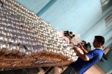 Genç adam Noel ağacı süslemek için el yapımı Noel topları üretimi için bir atölyede çalışıyor.