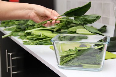 Yeşil meyve suyu hazırlama, sebzeler ahşap tahta üzerinde doğranır ve sağlıklı ve beslenme kahvaltısı için mutfaktaki miksere konur.