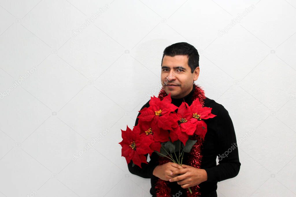 Latino adult man with Christmas hat shows Christmas decorations and decorations because he is ready to celebrate the holidays and the new year