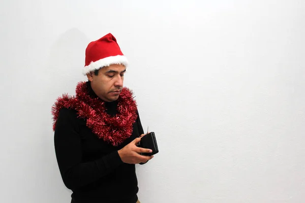 拿着帽子和圣诞花环的拉美裔成年人带着很少的钱展示他的皮夹 因为他们担心无法庆祝圣诞节 — 图库照片