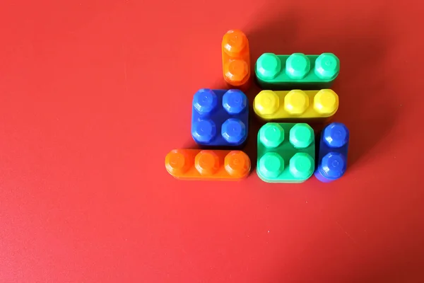Шматочки Пластикової Веселки Різнокольорові Будівельні Іграшкові Блоки Сформовані Розташовані Червоному — стокове фото