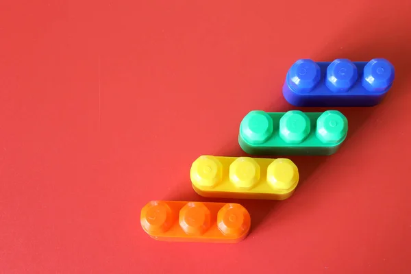 Шматочки Пластикової Веселки Різнокольорові Будівельні Іграшкові Блоки Сформовані Розташовані Червоному — стокове фото