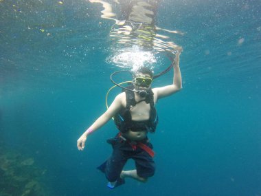 Latino adult man dives underwater with scuba equipment oxygen tank, visor, fins, enjoys sports and entertainment activity