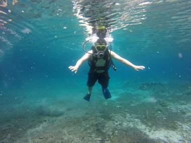 Latino adult man dives underwater with scuba equipment oxygen tank, visor, fins, enjoys sports and entertainment activity