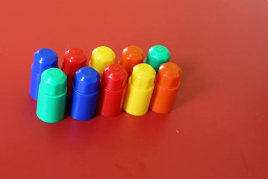 Buildable colored plastic blocks to play, build and organize on a red background as a concept of inclusion, diversity and plurality