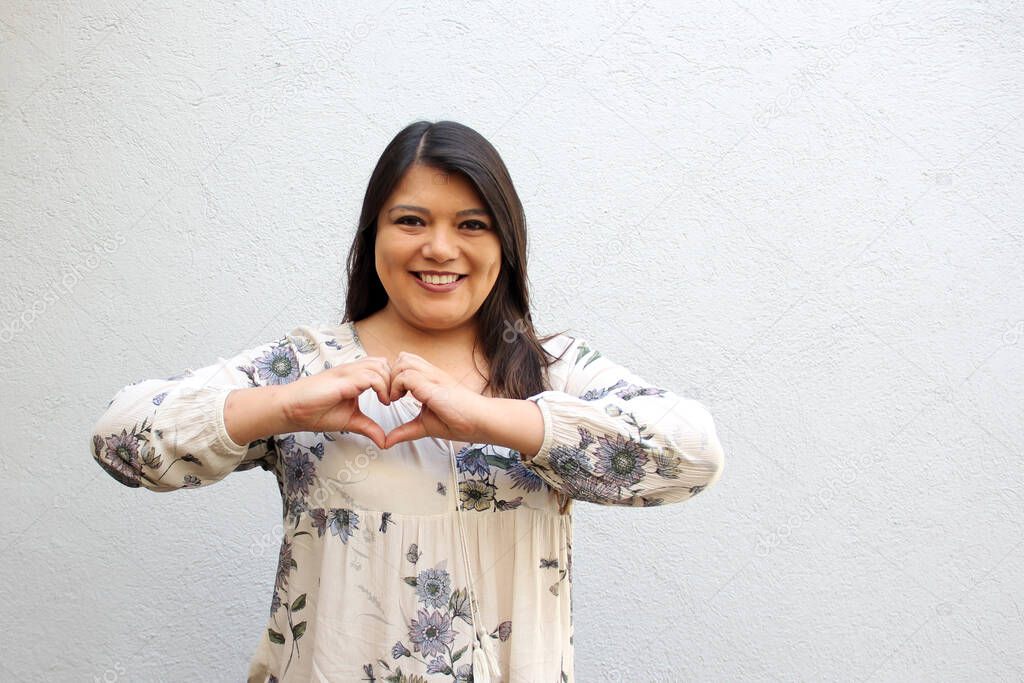 Latin adult woman shows big red heart with enthusiasm for the arrival of February and celebrate Valentine's Day of Love and Friendship with her family, friends and partner with happiness and affection