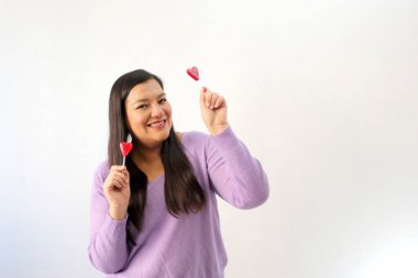 Kırmızı lolipopu olan Latin yetişkin bir kadın partneriyle kutlama yapmak için can atıyor. Sevgi ve Dostluk Günü Şubat ayında San Valentin 'de.