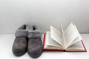 Rahat, pelüş ve yastıklı gri terlikler uyumaya, dinlenmeye ve yatağın yanında bir kitap, kahve ve bardakla dinlenmeye hazır.